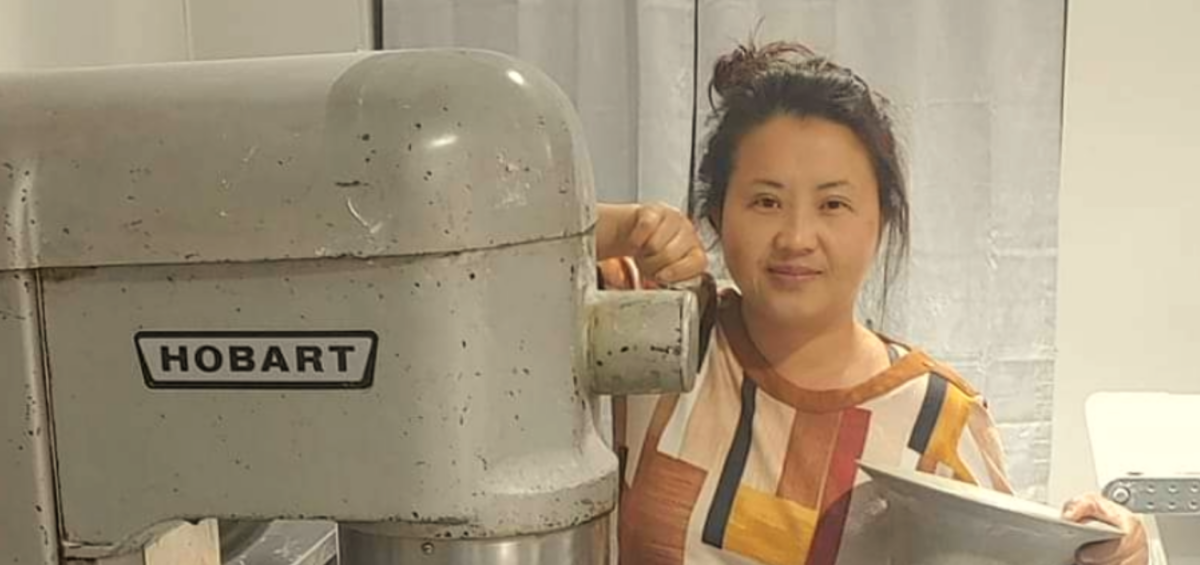 Melinda Vue posing with a commercial Hobart mixer